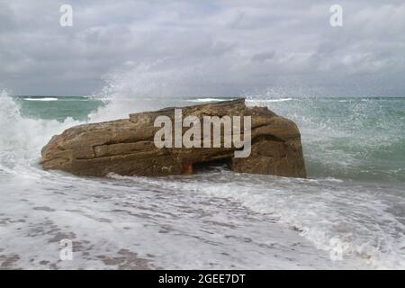 Waves splash against a German bunker from the second world war, fallen from te dunes in the sea in the Tannis Bugt in Denmark Stock Photo