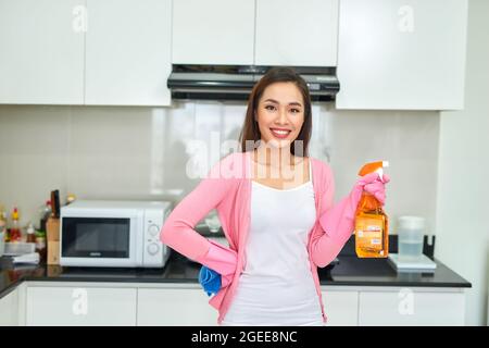 Young asian woman preparing to clean the kitchen. Hand holding detergent spray. Stock Photo