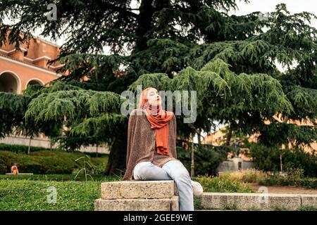 Stock photo of muslim woman sitting on a wall. She is wearing a hiyab Stock Photo