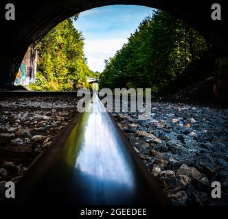 railway tracks going under a road underpass in nova scotia on a clear fall day Stock Photo