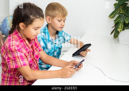 boy playing with smartphone next to his sister in the room at home. Stock Photo