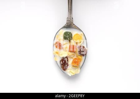 Healthy breakfast. Muesli with dried grapes is poured with milk in a spoon on a white wooden table. Space for text. Stock Photo