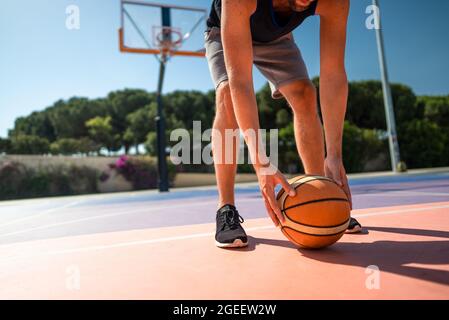 basketball player on the playground picks up the ball from the ground. Stock Photo