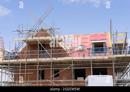 new house with new roof being built on sunny summer day , blue sky, scaffoldings, red brick wall, Buckinghamshire England Stock Photo