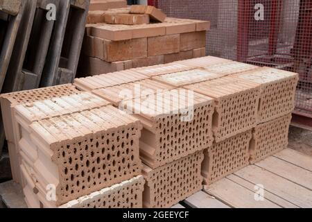 Stack of Red clay Ceramic Bricks over Euro pallets, construction site Stock Photo