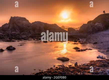 The setting sun shrouded in thick fog on Battery Point Beach, Crescent City California. Stock Photo