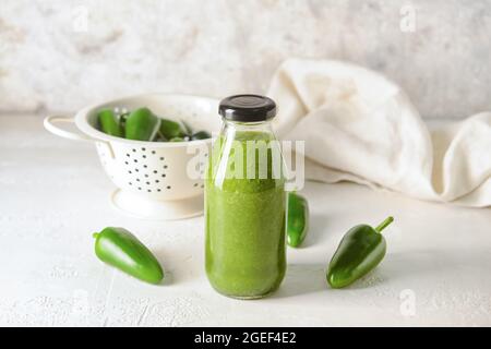 Bottle of Tomatillo Salsa Verde sauce and jalapeno pepper on light background Stock Photo