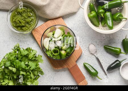 Blender with ingredients for Tomatillo Salsa Verde sauce on light background Stock Photo