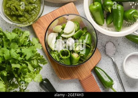 Blender with ingredients for Tomatillo Salsa Verde sauce on light background Stock Photo