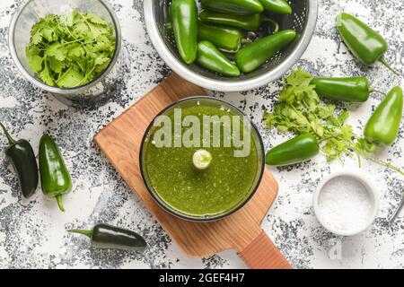 Blender with Tomatillo Salsa Verde sauce and ingredients on grunge background Stock Photo