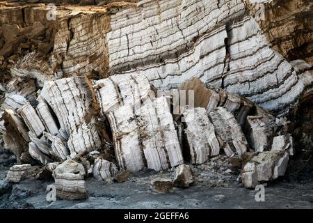 Annual layers of salt and minerals deposited on the shore of the Dead Sea being exposed by dropping water level, Israel Stock Photo