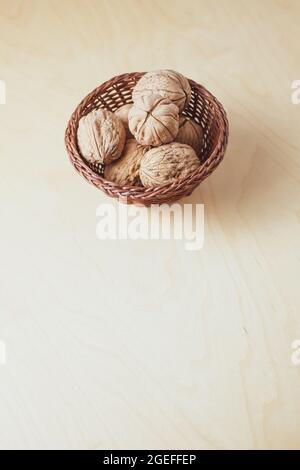 Vertical shot of whole walnuts in a small basket isolated on a beige background Stock Photo