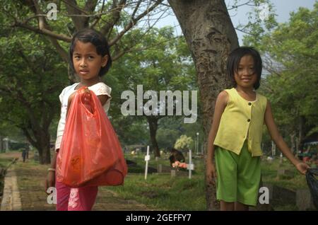 Portrait of children who are working by collecting plastic waste at Pondok Kelapa public cemetery in East Jakarta, Indonesia. Some of them work on daily basis; mostly by offering service of grave cleaning. Stock Photo