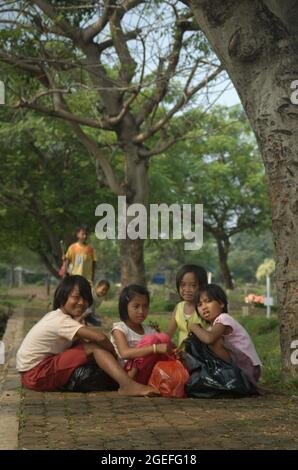 Portrait of children who are working by collecting plastic waste at Pondok Kelapa public cemetery in East Jakarta, Indonesia. Some of them work on daily basis; mostly by offering service of grave cleaning. Stock Photo