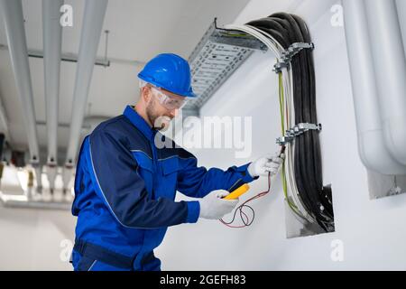 Electrician Doing Cable Installation And Maintenance In Office Stock Photo