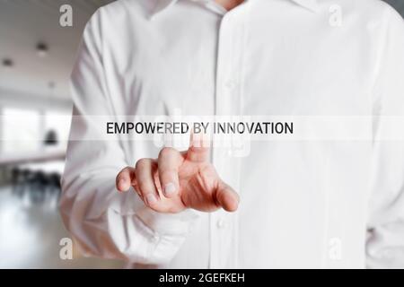 Businessman presses on virtual touch screen with the words empowered by innovation. Business industry innovation, creativity and development concept. Stock Photo