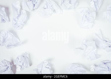 Crumpled sheets of paper on white background with blank space in the center, top view. Stock Photo