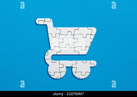 Shopping cart symbol made out of puzzle pieces on blue background. Stock Photo