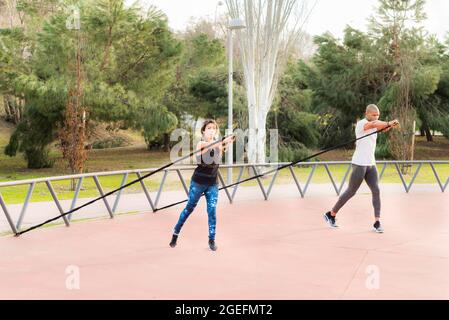 Fitness couple exercising with a fitness strap in the park Stock Photo