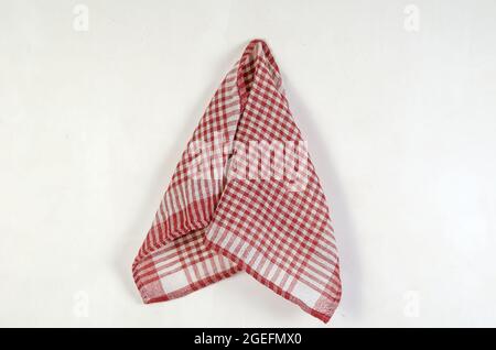 Red checkered napkin against a gray wall. Cotton napkin hanging vertically. A gray cement wall with scratches. Stock Photo