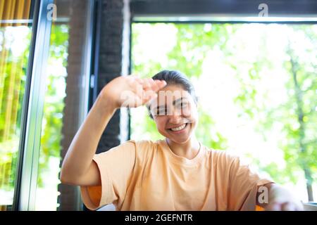Headshot of indian woman sit on potdoor cafe waving hand looks to camera make video call chat use computer laptop webcam view, vlogger record webinar, job interview distantly concept. Stock Photo