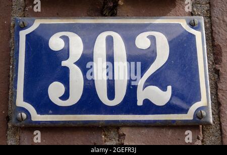 A sign on a wall with the number three hundred two-302 Stock Photo