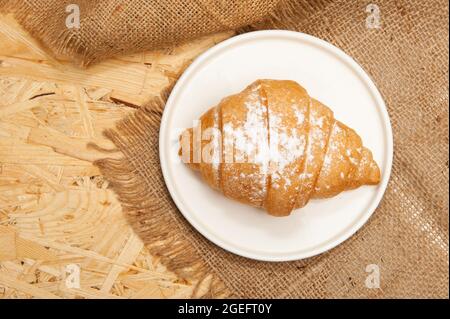 Croissant on a saucer and on a canvas napkin. Top view Stock Photo