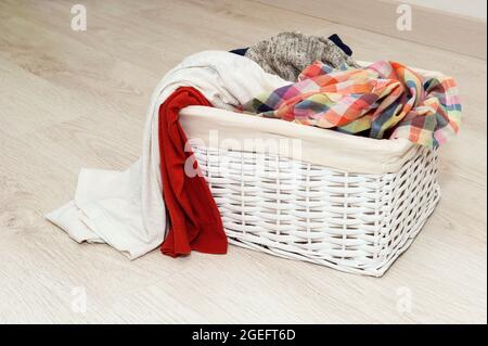 Dirty bedding in a white wicker basket on the floor Stock Photo