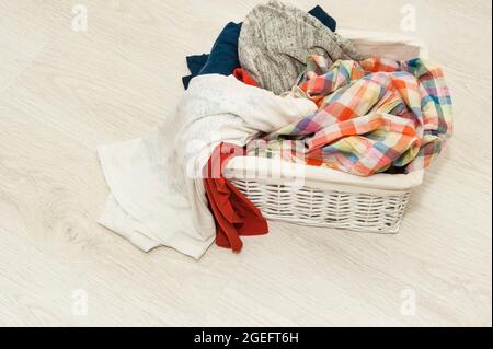 Dirty bedding in a white wicker basket on the floor Stock Photo