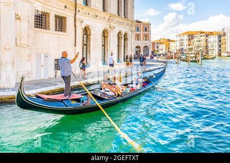 VENICE, ITALY - AUGUST 02, 2021: Tourists and gondolier on gondola boat. Romantic gondola cruise in Venetian water canal, Venice, Italy. Stock Photo