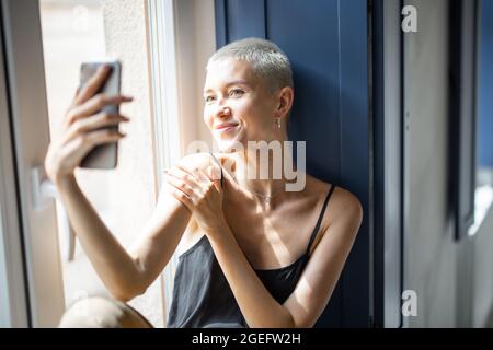 Stylish woman talking on phone at window Stock Photo