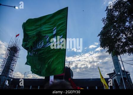 A Kashmiri Shia Muslim man waves a religious flag during the Ashura ...