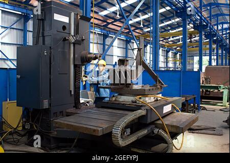 A worker is operating a horizontal boring and milling machine in a fabrication workshop. Stock Photo