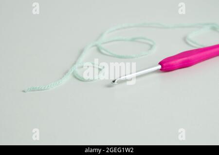 knitting pink crochet hooks and woolen thread on a blue background