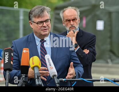 Doberlug Kirchhain, Germany. 20th Aug, 2021. Olaf Jansen, head of Brandenburg's Central Foreigners Authority, speaks at a press conference on the grounds of the DRK Refugee Aid in the initial reception facility. In the background is Markus Grünewald, State Secretary of the Brandenburg Ministry of the Interior. Early this morning, at around 4:30 a.m., two buses from the airport in Frankfurt am Main arrived here at the Central Foreigners Authority of Brandenburg with almost 59 local people from Afghanistan. Credit: Patrick Pleul/dpa-Zentralbild/dpa/Alamy Live News
