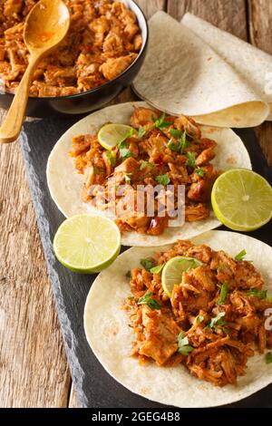 Chilorio is a pork dish from the Mexican state of Sinaloa served with tortilla and lime closeup in the slate board on the table. Vertical Stock Photo