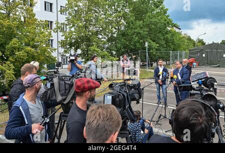Doberlug Kirchhain, Germany. 20th Aug, 2021. Olaf Jansen (2nd from right), head of the Central Foreigners Authority of Brandenburg, speaks at a press conference on the grounds of the DRK Refugee Aid at the initial reception facility. Early in the morning, at around 4:30 a.m., two buses from the airport in Frankfurt am Main arrived here at the Central Foreigners Authority of Brandenburg with almost 59 local staff from Afghanistan. Credit: Patrick Pleul/dpa-Zentralbild/dpa/Alamy Live News