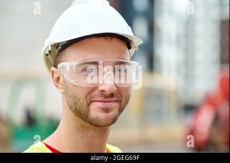 Pleased attractive builder in safety goggles posing for the camera Stock Photo
