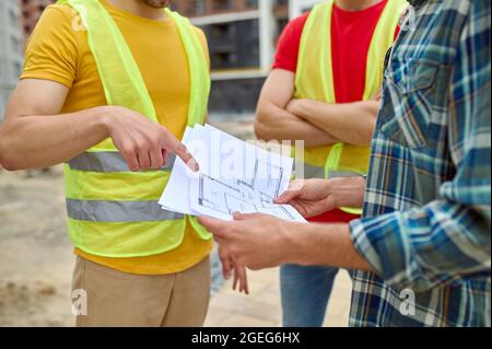 Three adult men discussing a new house plan outdoors Stock Photo
