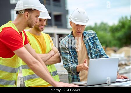 Three colleagues discussing a new building project outdoors Stock Photo