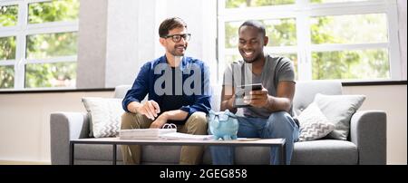 Happy Gay Couple Doing Taxes And Income Planning With Calculator Stock Photo