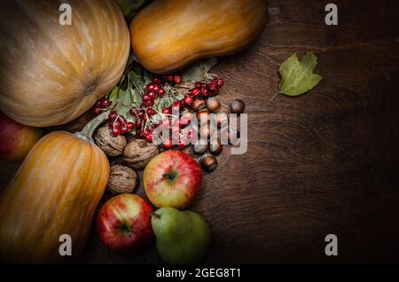 autumn background with pumpkin, fruits and nuts on dark wooden background Stock Photo