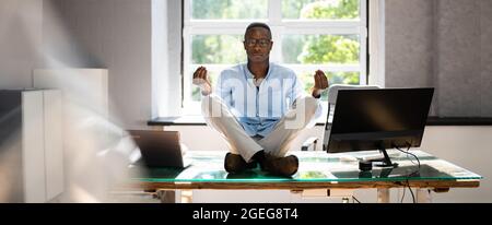 African Employee Doing Mental Health Yoga Meditation In Office Stock Photo