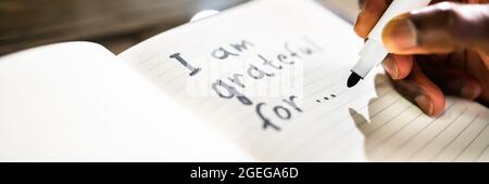African American Man Writing In Gratitude Journal Stock Photo