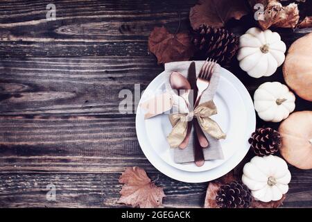 A holiday place setting with plate, napkin, on a Thanksgiving Day decorated table shot from flat lay or top view position. Silverware tied with gold r Stock Photo