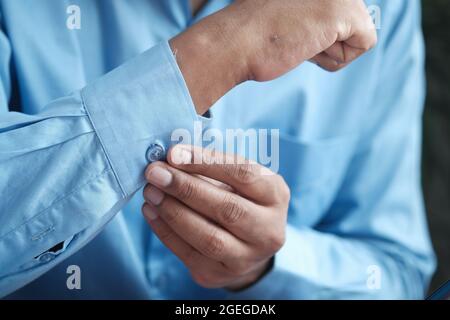 Man buttoning his shirt close up Stock Photo