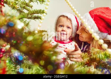 Happy toddler boy with mother near Christmas tree Stock Photo