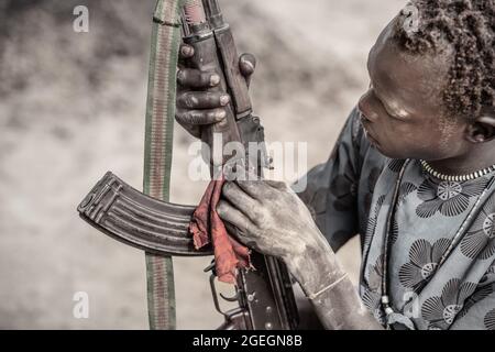 Maintaining and cleaning the guns is an important aspect of keeping them functional. TEREKEKA, SOUTH SUDAN: In one image, a man stared into the camera Stock Photo