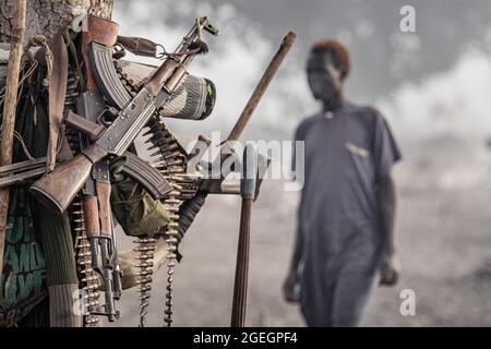 A collection of guns. TEREKEKA, SOUTH SUDAN: In one image, a man stared into the camera surrounded by cows while brandishing a huge machine gun. In an Stock Photo