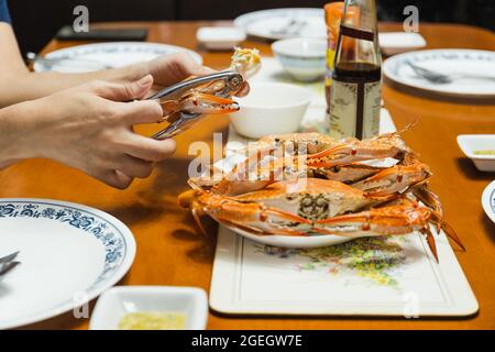 Woman eating crab claw using special pliers tool. Stock Photo